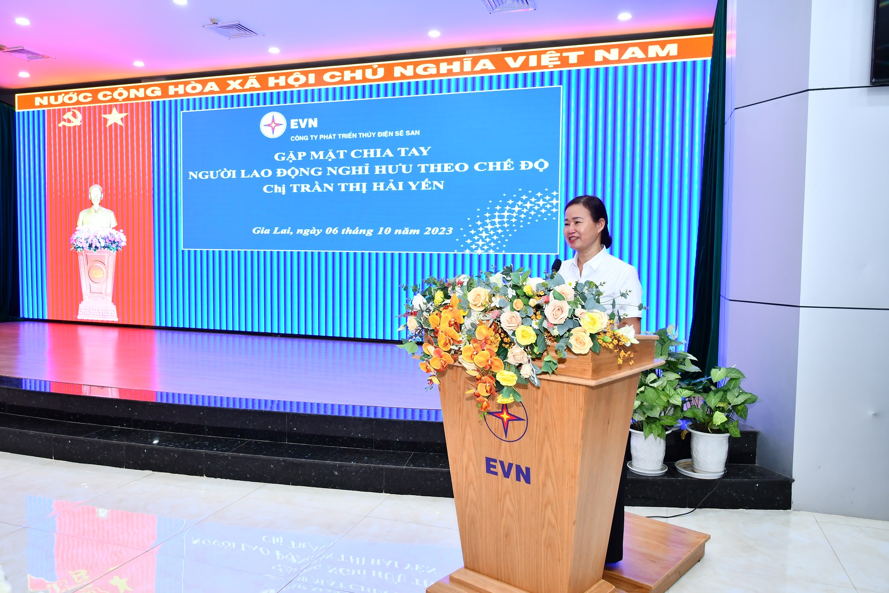 A person standing at a podium with flowersDescription automatically generated