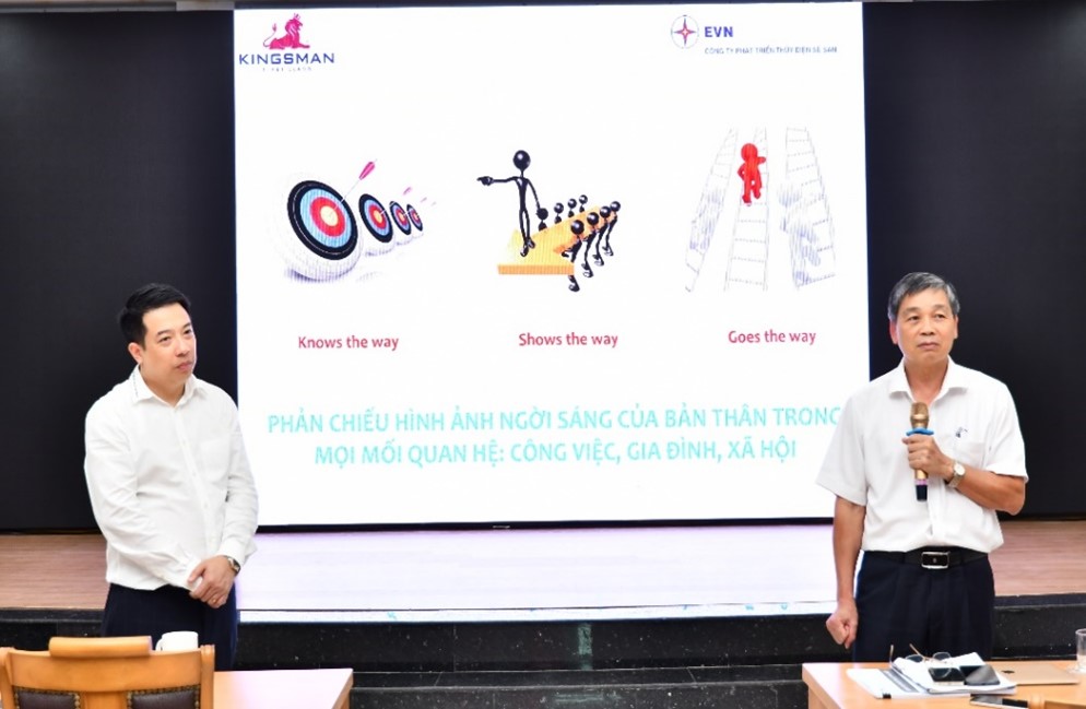 A group of men standing in front of a projection screenDescription automatically generated