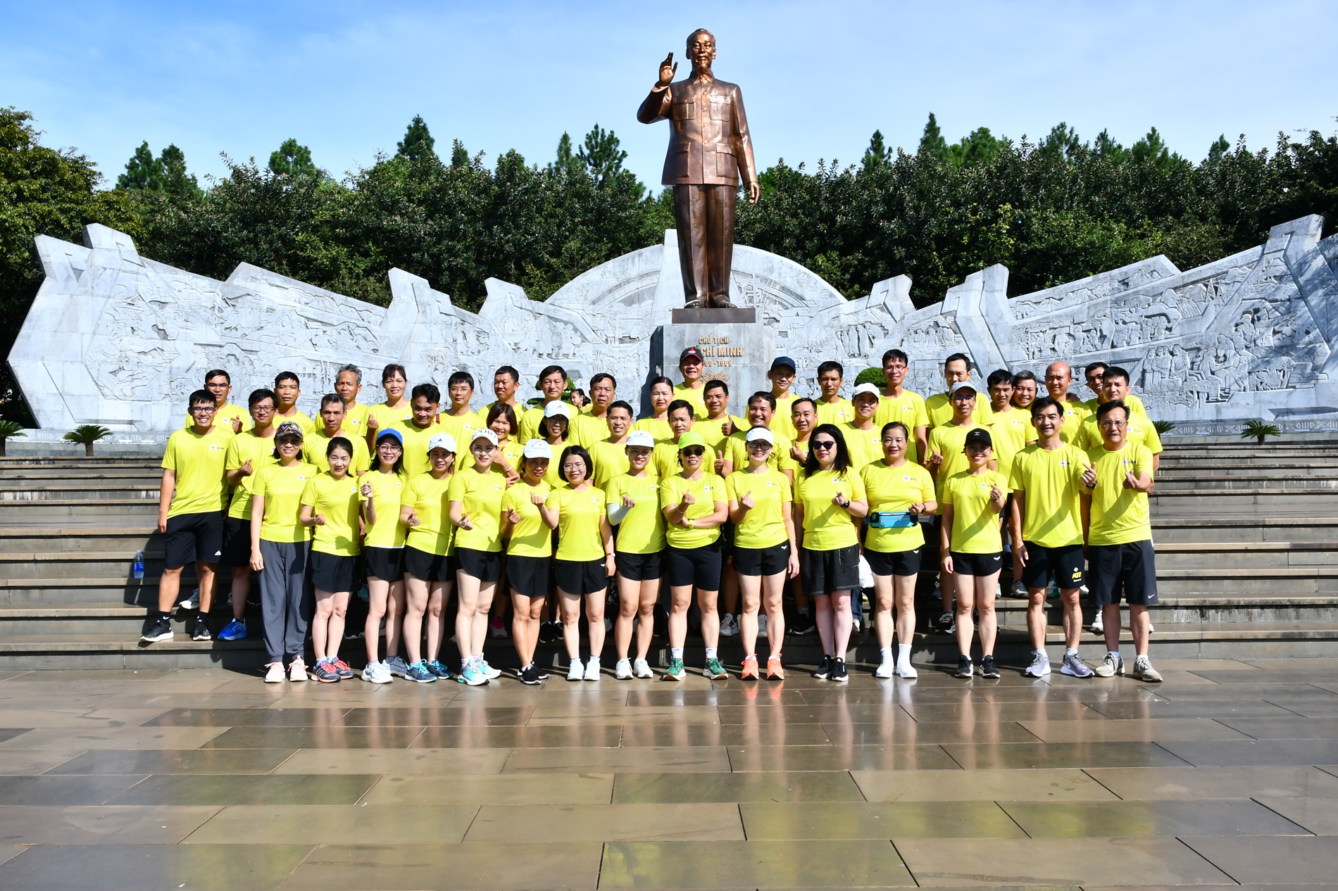 A group of people in yellow shirts posing for a photoDescription automatically generated
