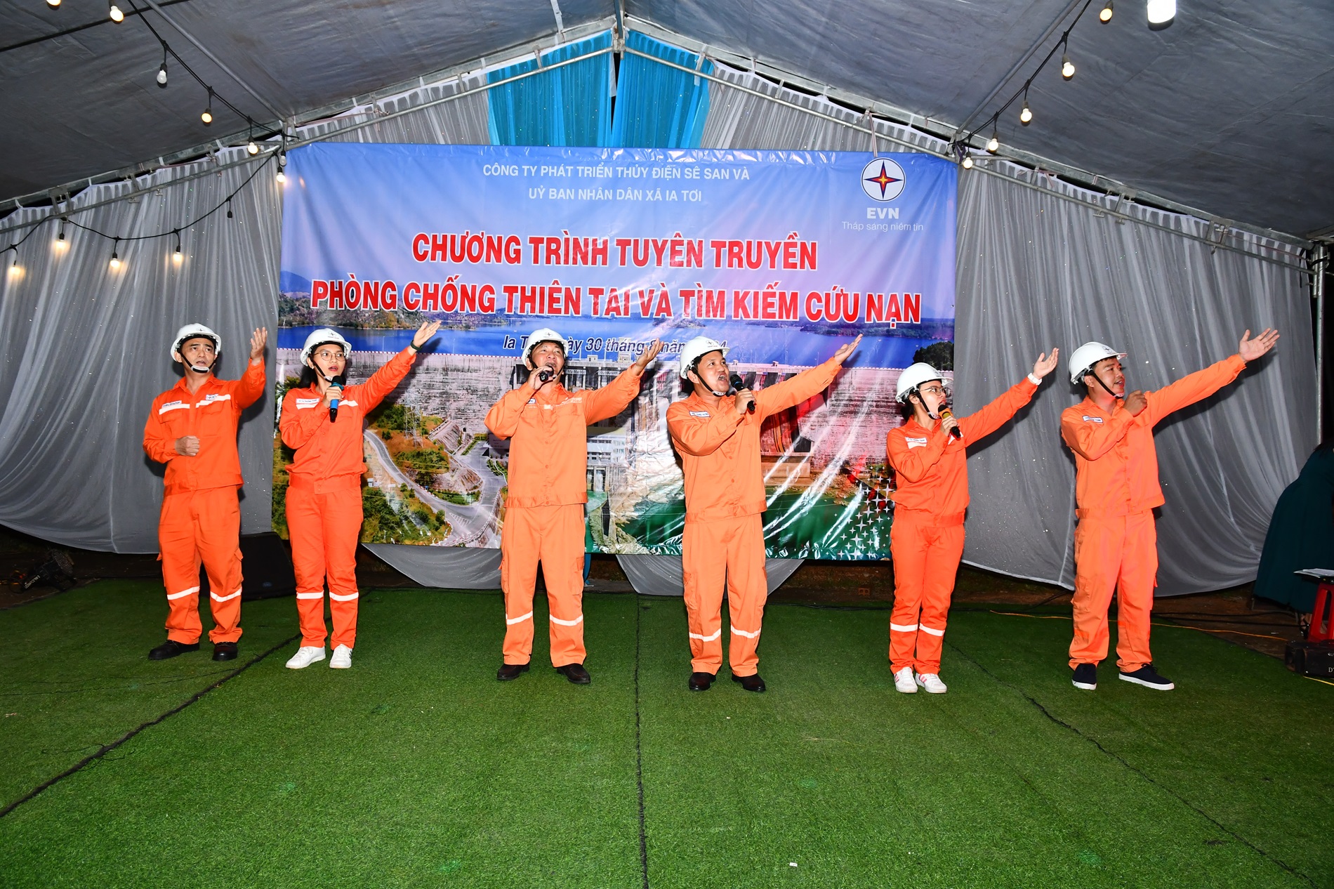 A group of people wearing orange jumpsuits and helmetsDescription automatically generated